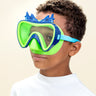 boy smiling wearing blue fish kids' swim mask showing green nose piece and blue frame with two silicone blue fishes above the frame