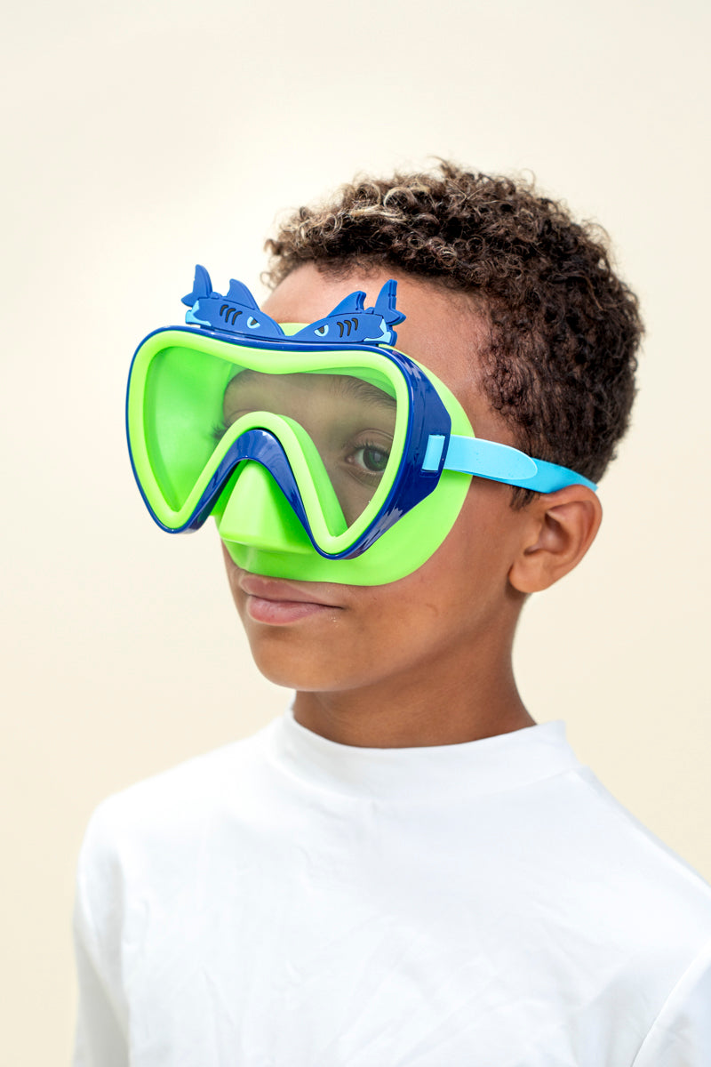 boy smiling wearing blue fish kids' swim mask showing green nose piece and blue frame with two silicone blue fishes above the frame