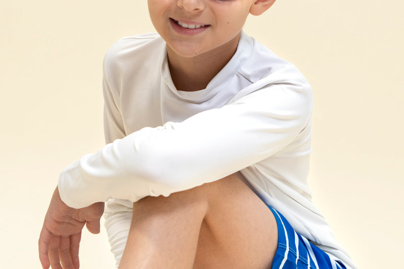 boy smiling and posing wearing mini mako shark kids swim goggles featuring a blue swim goggle with a silicone shark wrapping around the top of the lenses with a blue nose piece and blue strap