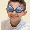 boy smiling wearing mini mako shark kids swim goggles featuring a blue swim goggle with a silicone shark wrapping around the top of the lenses with a blue nose piece and blue strap