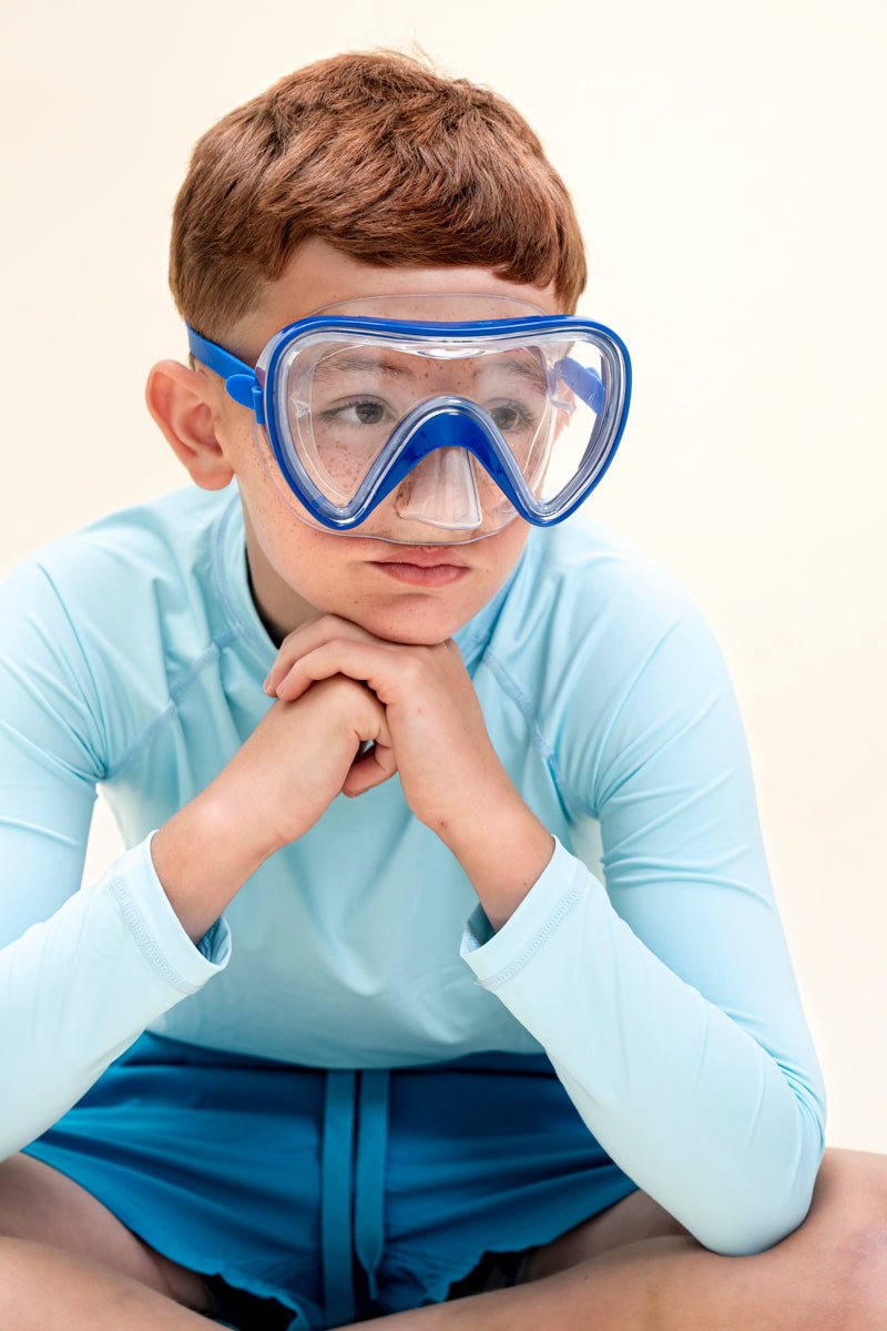 boy posing and wearing splash in color blue kids swim mask featuring a clear gasket and nose covering with a bright blue frame and strap