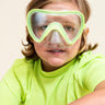 boy sitting smiling wearing splash in color green kids' swim mask showing a clear gasket and nose covering featuring a lime green frame and strap