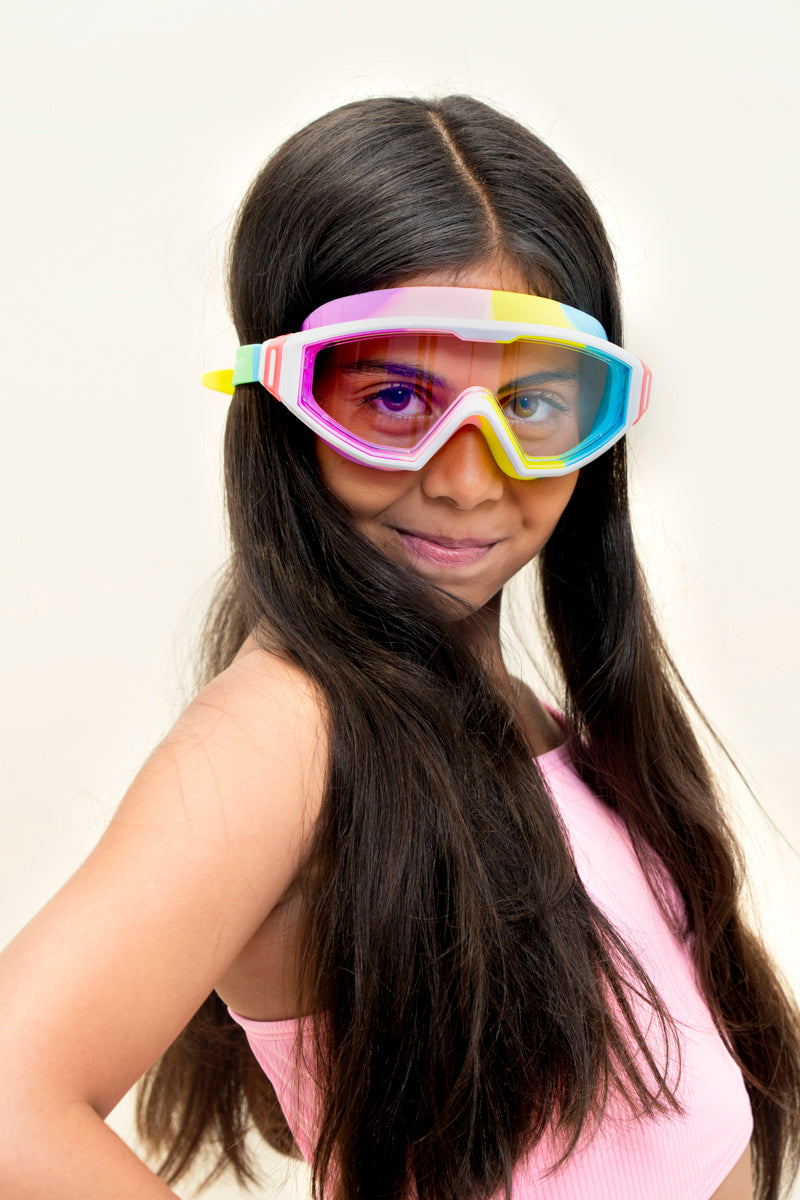 girl smiling wearing panoramic rainbow kids swim goggles which feature a panoramic wide frame and a rainbow colored silicone gasket