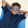 boy laying in inner tube posing wearing blue camo kids' swim goggles which feature a blue camo print on the frame