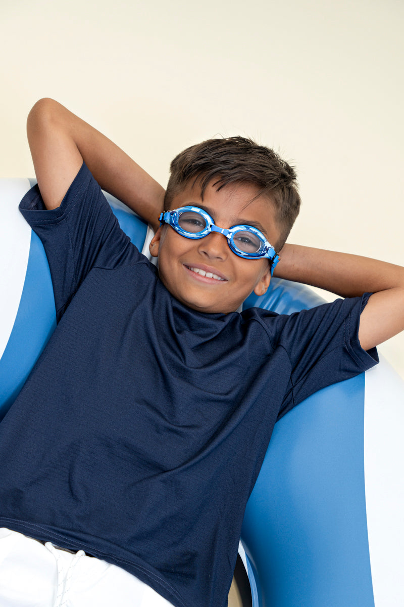 boy laying in inner tube posing wearing blue camo kids' swim goggles which feature a blue camo print on the frame